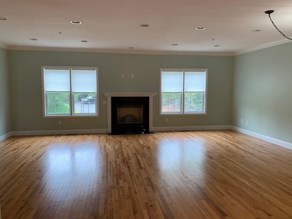 3 Dansereau Place, Unit 3 Middleton, MA 01949 - Photo 10 of 34 an empty room with wooden floor fireplace and windows
