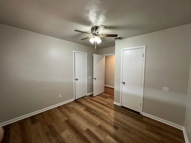 an empty room with closet and a ceiling fan