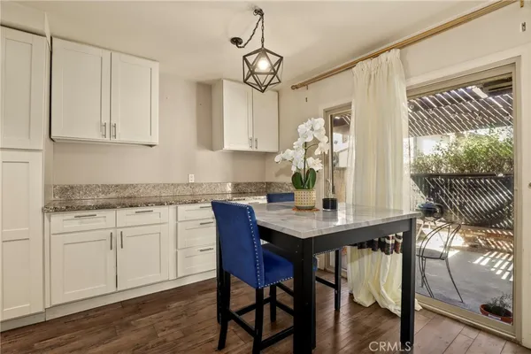 a kitchen with stainless steel appliances granite countertop a dining table chairs stove refrigerator and cabinets