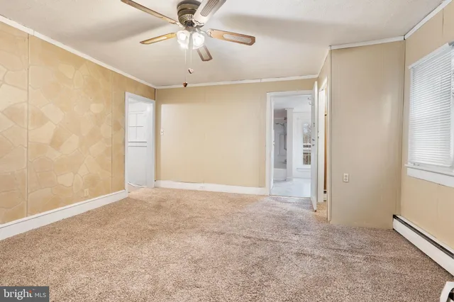an empty room with chandelier fan and windows