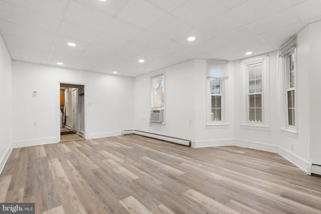 a view of an empty room with wooden floor and windows