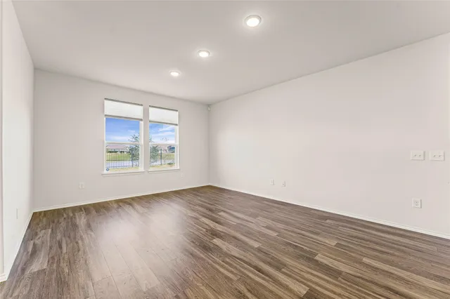 an empty room with wooden floor and a kitchen