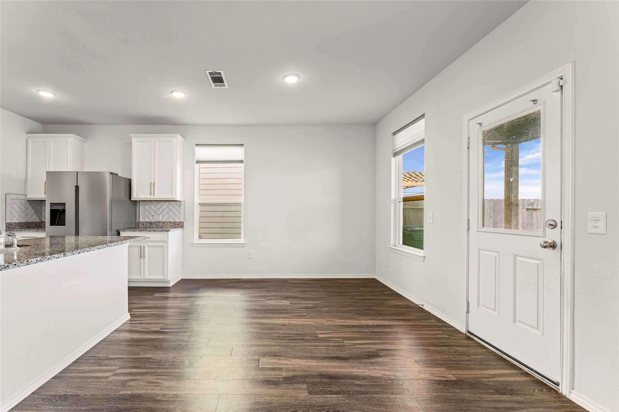 5826 Savanna Pasture Road Katy, TX 77493 - Photo 25 of 45 an empty room with wooden floor and a kitchen