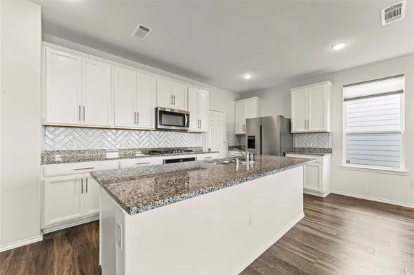 a large kitchen with stainless steel appliances granite countertop a lot of counter space and a sink