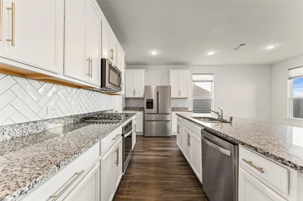 a large kitchen with stainless steel appliances granite countertop a lot of counter space and wooden floors