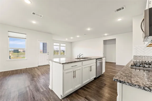 a kitchen with granite countertop a sink stove and cabinets