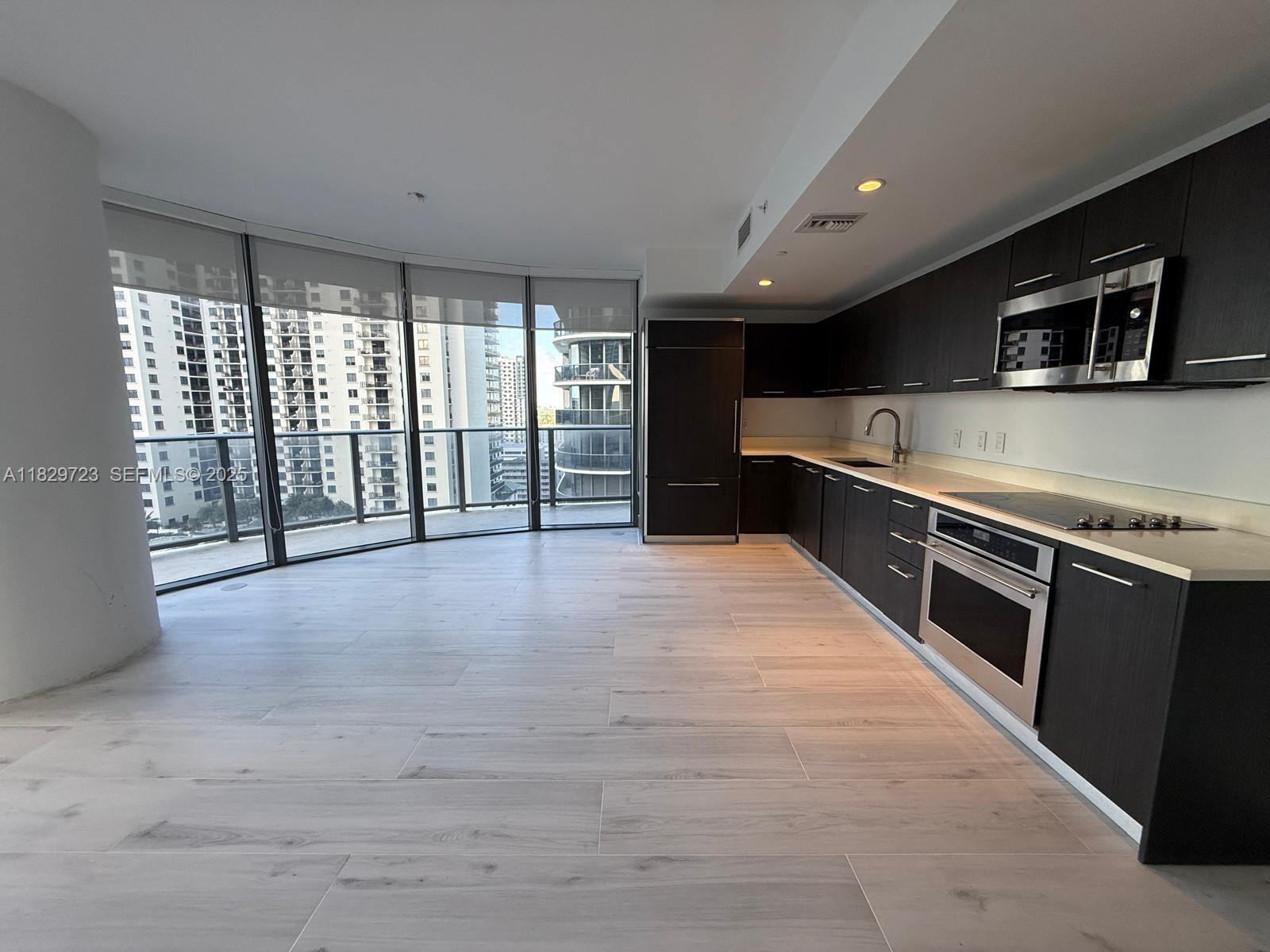 45 Southwest 9th Street, Unit 1706 Miami, FL 33130 - Photo 3 of 29 a large kitchen with stainless steel appliances a large counter top a stove a microwave and a refrigerator