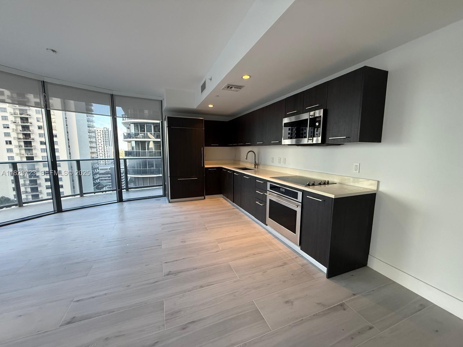 45 Southwest 9th Street, Unit 1706 Miami, FL 33130 - Photo 4 of 29 a large kitchen with stainless steel appliances wooden cabinets and a wooden floor