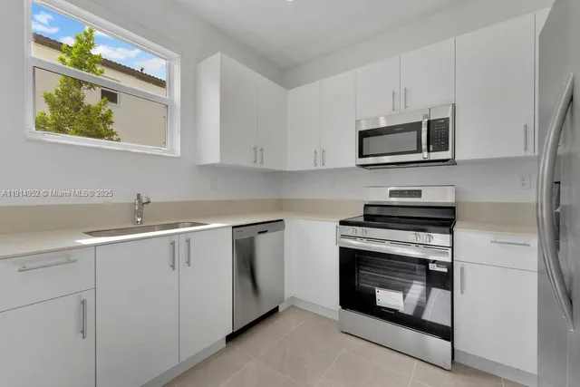 a kitchen with cabinets stainless steel appliances a sink and a microwave