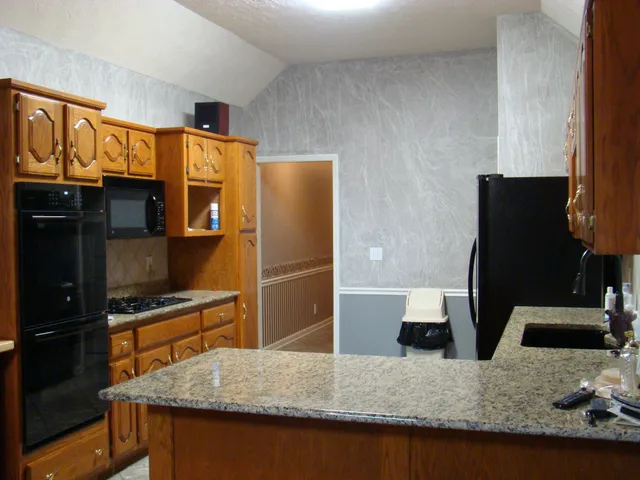 a kitchen with stainless steel appliances granite countertop a sink and a refrigerator