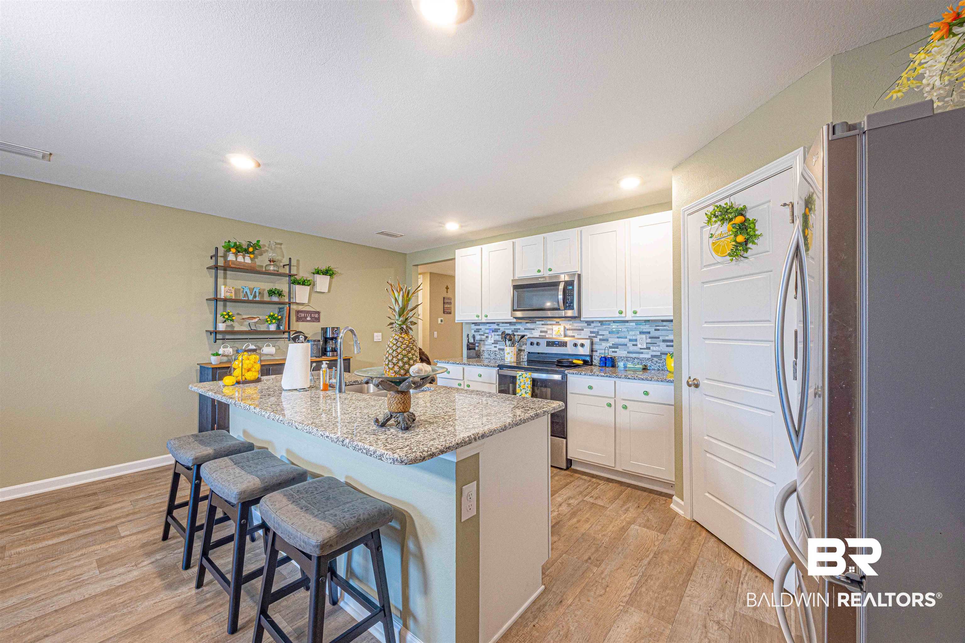 14843 Forsythia Loop Silverhill, AL 36576 - Photo 15 of 51 Kitchen featuring a kitchen breakfast bar, stainless steel appliances, a center island with sink, light wood-type flooring, and light stone countertops