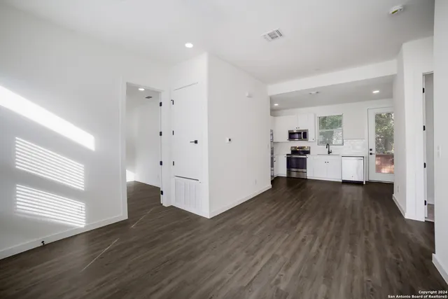 a kitchen with a sink wooden floor and stainless steel appliances