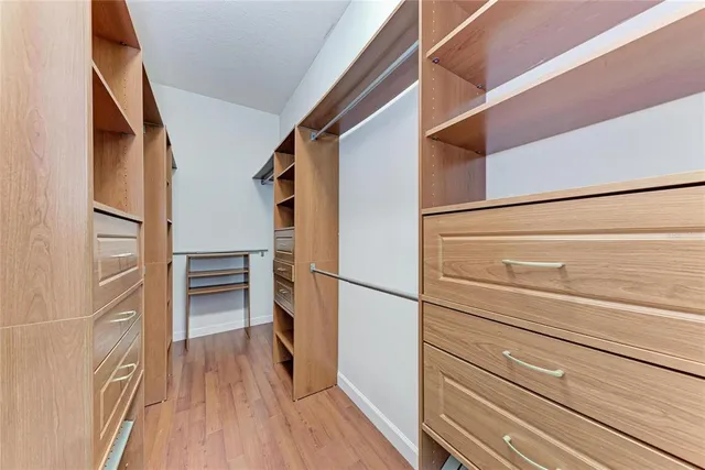 an empty room with wooden floor ceiling fan and windows