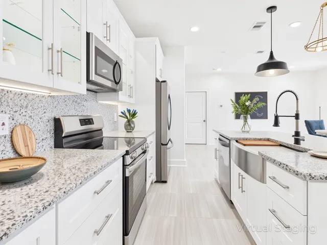 511 Richardson Street Athens, TX 75751 - Photo 13 of 40 Kitchen featuring appliances with stainless steel finishes, white cabinets, light stone countertops, pendant lighting, and tasteful backsplash