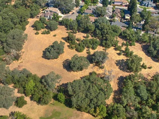 an aerial view of residential house with outdoor space and trees all around