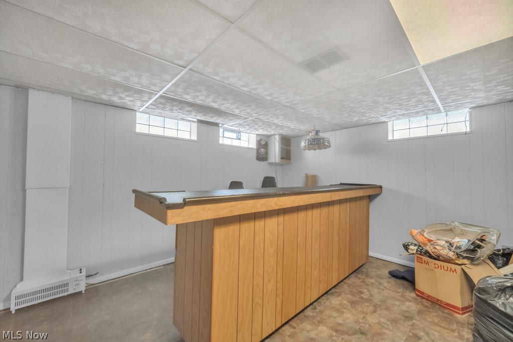 6846 Revere Road Cleveland, OH 44130 - Photo 25 of 30 Indoor dry bar with wooden walls, dark countertops, and wood finish cabinets