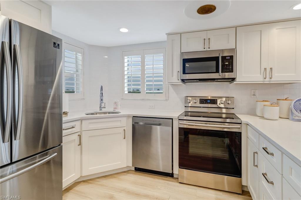 21 High Point Circle East, Unit 601 Naples, FL 34103 - Photo 12 of 22 a kitchen with white cabinets stainless steel appliances and a window