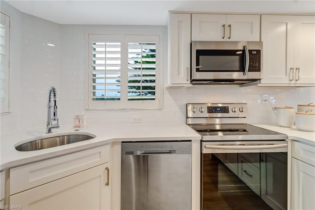 21 High Point Circle East, Unit 601 Naples, FL 34103 - Photo 13 of 22 a kitchen with stainless steel appliances a stove microwave and sink