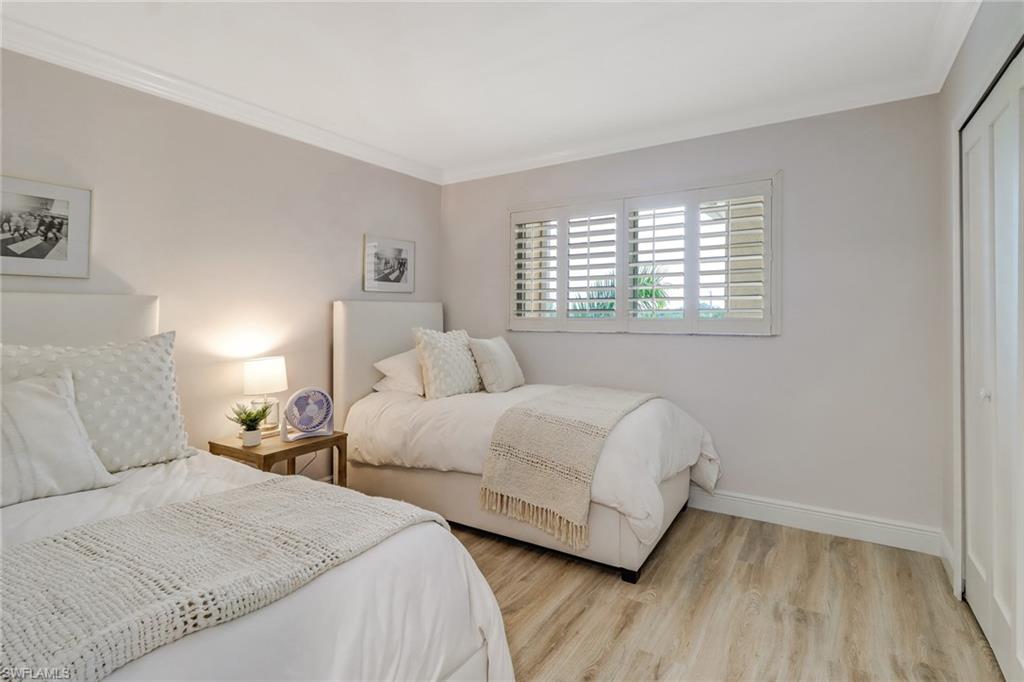 21 High Point Circle East, Unit 601 Naples, FL 34103 - Photo 14 of 22 a bedroom with two beds and a wooden floor