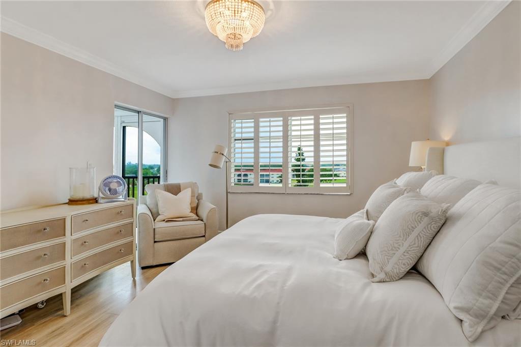 21 High Point Circle East, Unit 601 Naples, FL 34103 - Photo 18 of 22 a bedroom with a large bed and a chandelier