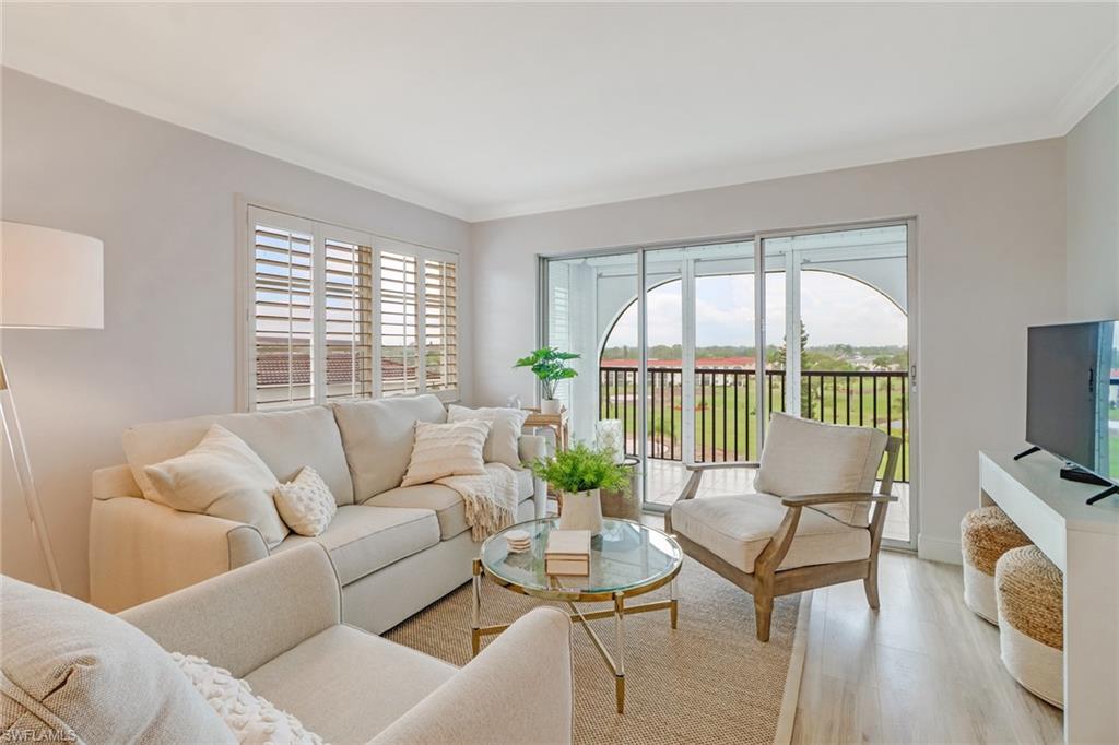 21 High Point Circle East, Unit 601 Naples, FL 34103 - Photo 5 of 22 a living room with furniture a flat screen tv and a floor to ceiling window