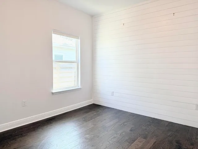 an empty room with wooden floor chandelier fan and windows
