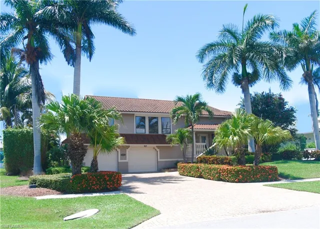a view of a house with a yard and palm trees