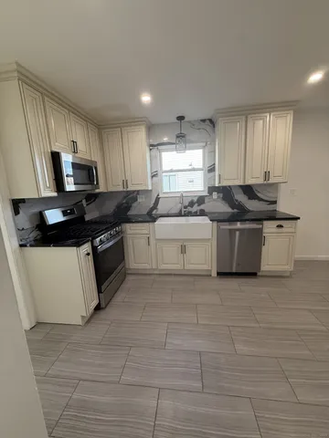 a kitchen with stainless steel appliances a stove a sink a microwave and a refrigerator