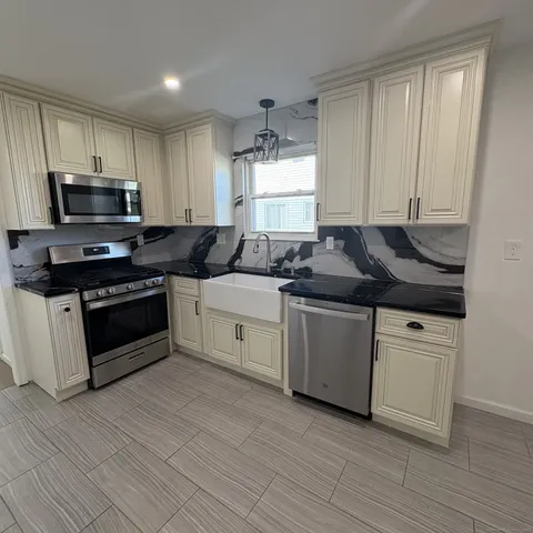 a kitchen with stainless steel appliances granite countertop a stove a sink and a microwave