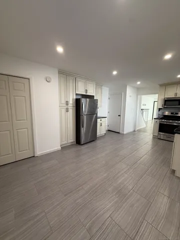 a view of kitchen appliances wooden floor and cabinets