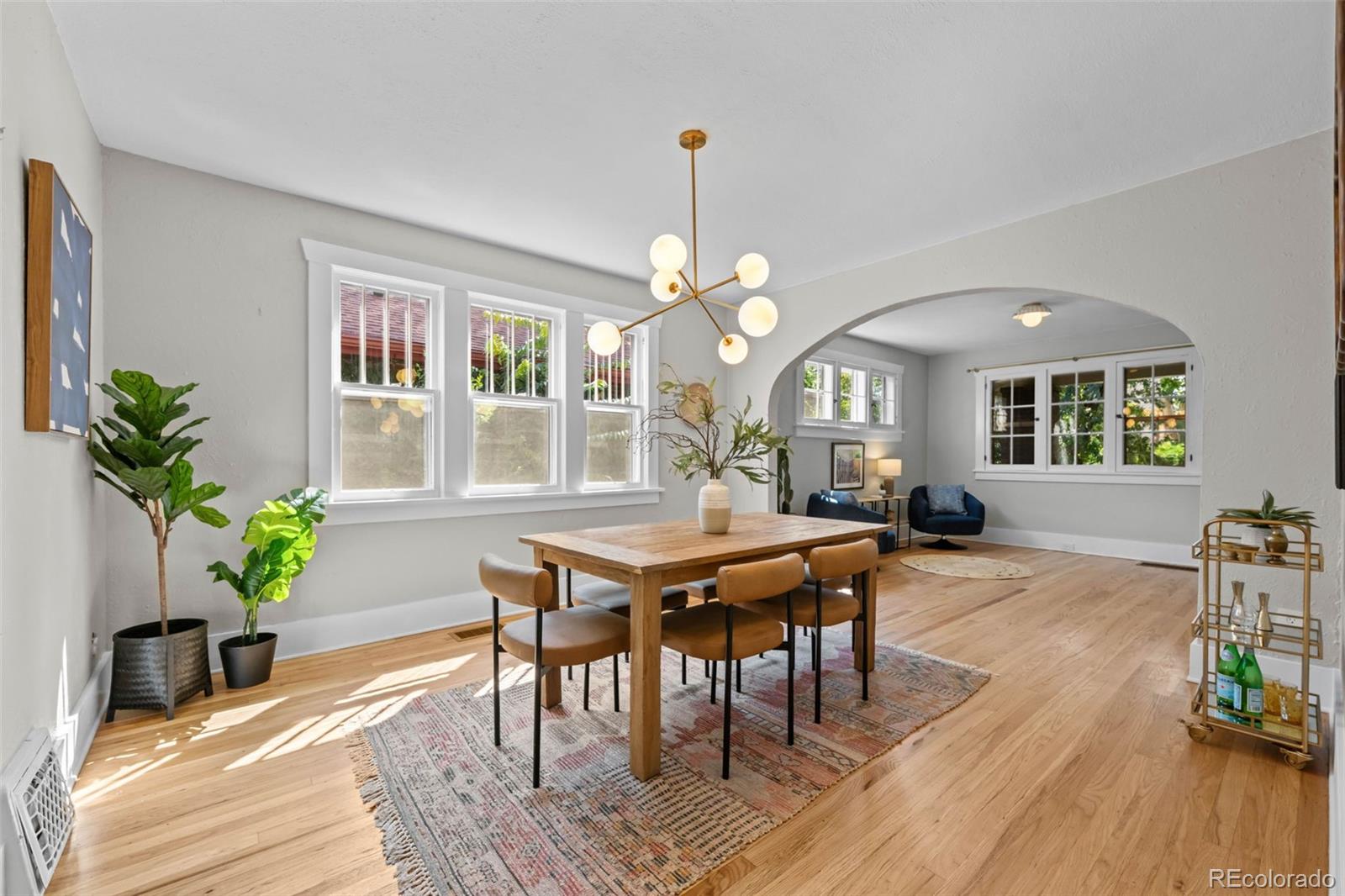 2314 Grape Street Denver, CO 80207 - Photo 15 of 49 a dining room with wooden floor a chandelier a wooden table and chairs