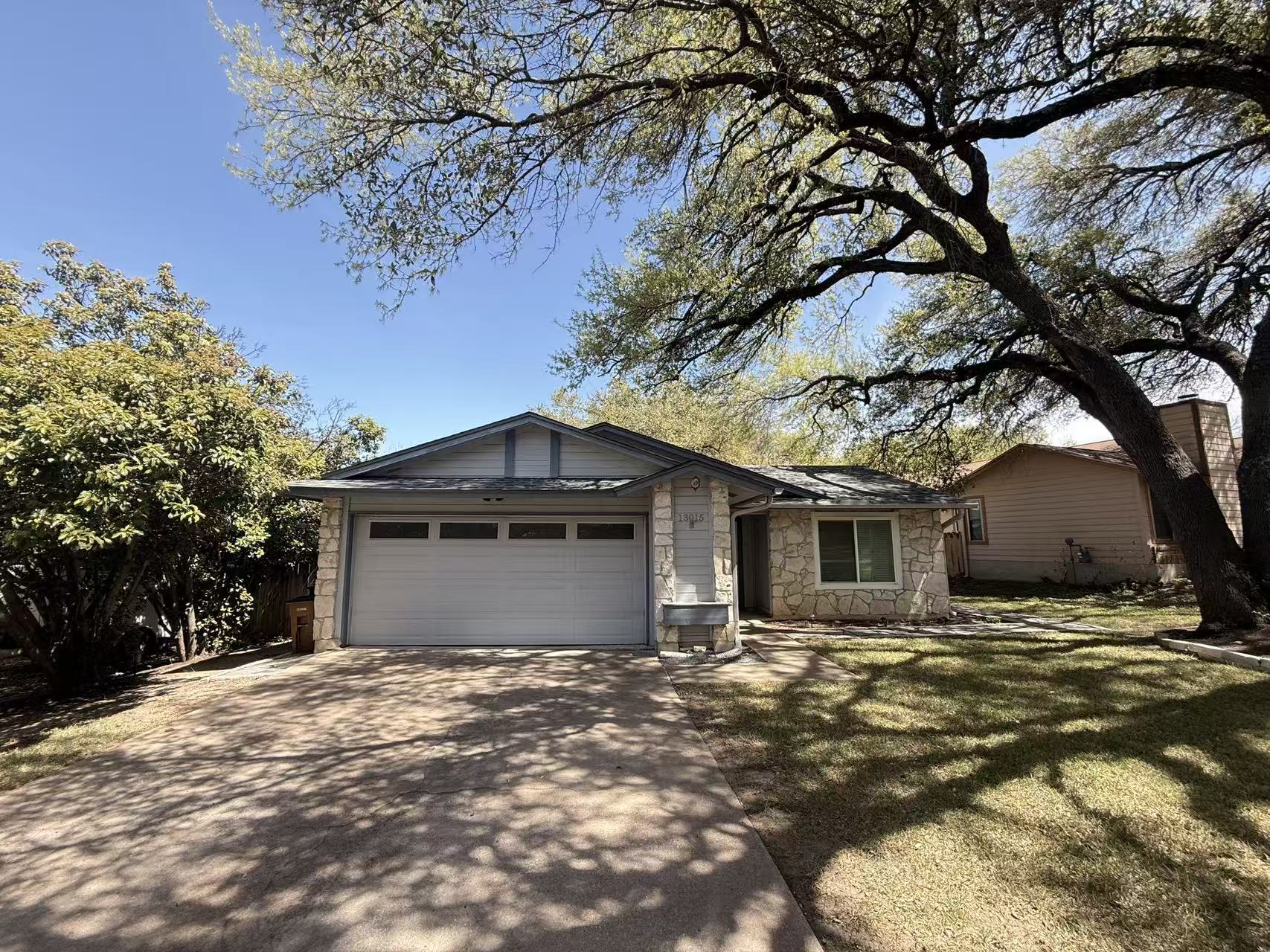 13015 Garfield Lane Austin, TX 78727 - Photo 1 of 16 View of front of property featuring stone siding, a garage, concrete driveway, and a front lawn