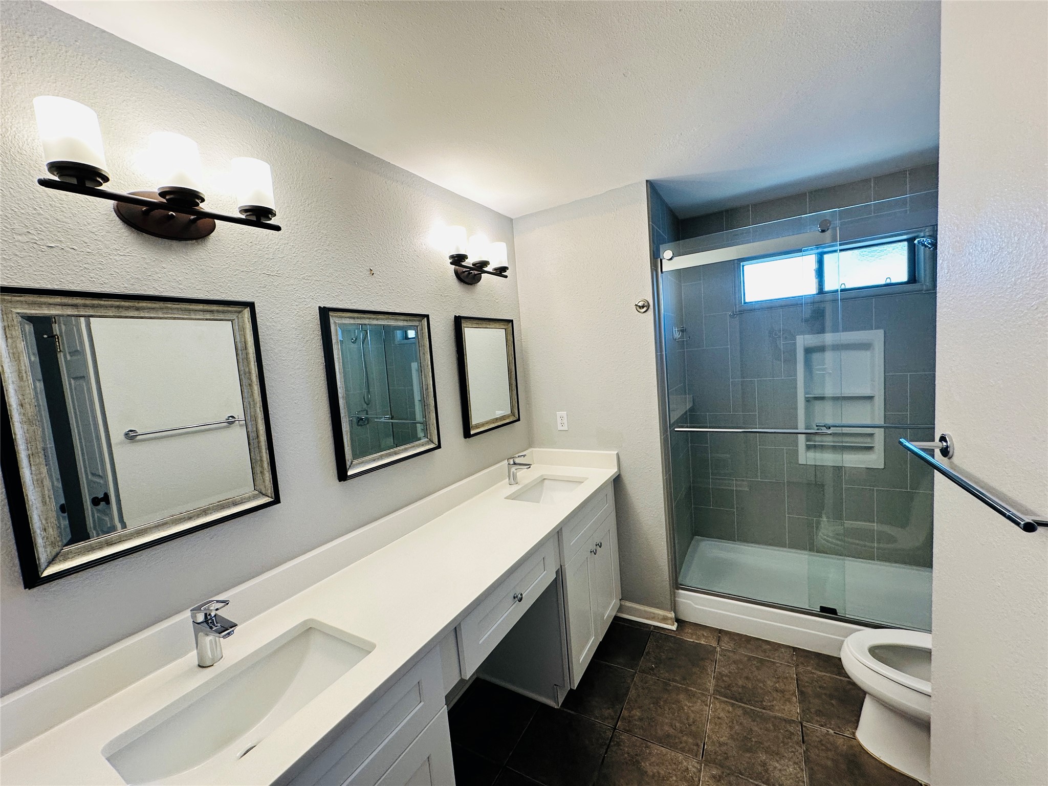 13015 Garfield Lane Austin, TX 78727 - Photo 13 of 16 Bathroom with double vanity, a stall shower, and a textured wall