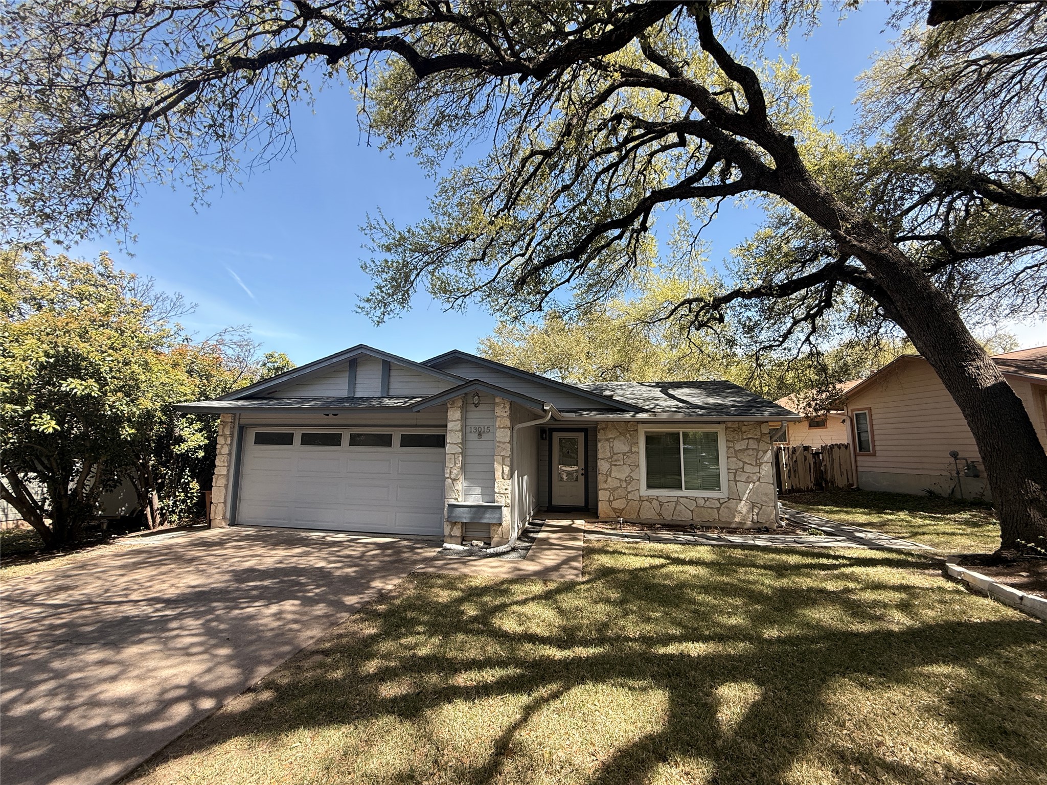 13015 Garfield Lane Austin, TX 78727 - Photo 2 of 16 View of front of house with a garage, stone siding, and driveway