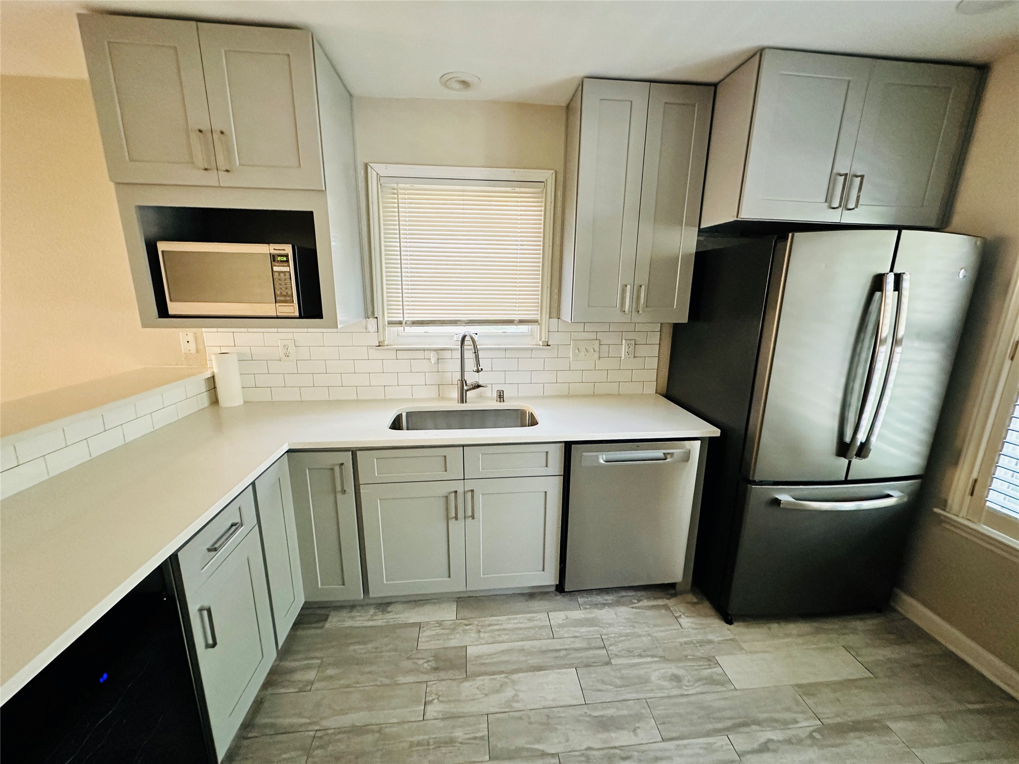 13015 Garfield Lane Austin, TX 78727 - Photo 4 of 16 Kitchen with stainless steel appliances, gray cabinets, tasteful backsplash, and light stone counters