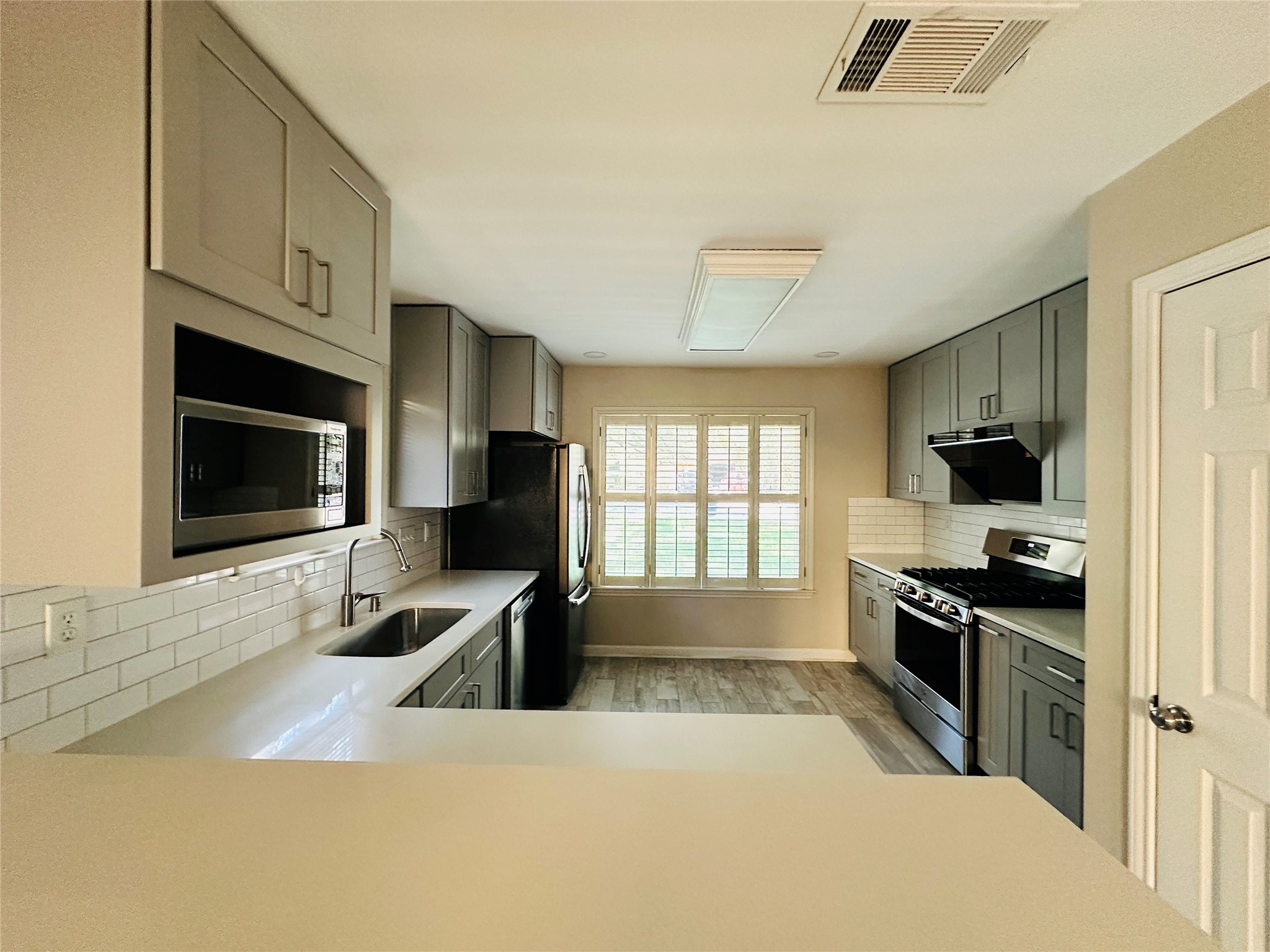 13015 Garfield Lane Austin, TX 78727 - Photo 5 of 16 Kitchen featuring gray cabinets, stainless steel appliances, light wood-type flooring, and decorative backsplash