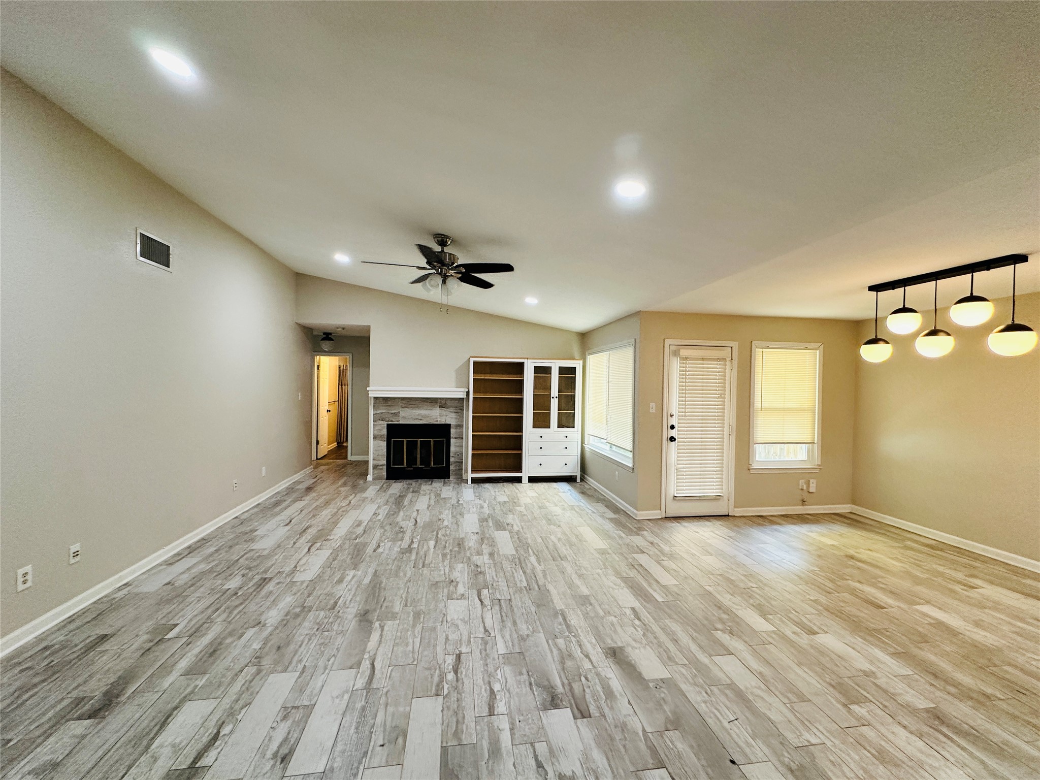 13015 Garfield Lane Austin, TX 78727 - Photo 7 of 16 Unfurnished living room featuring light wood-type flooring, a fireplace, recessed lighting, lofted ceiling, and a ceiling fan