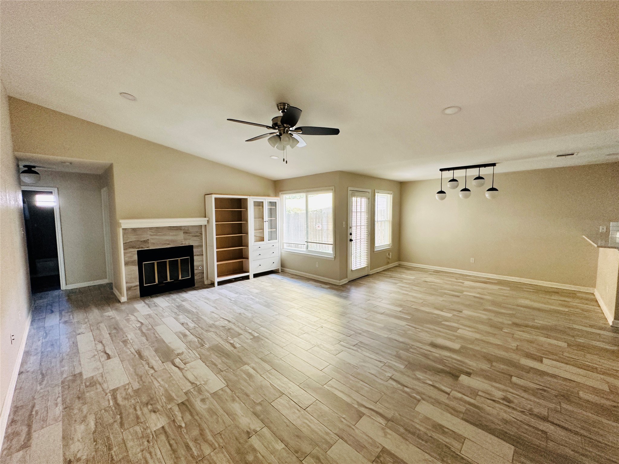 13015 Garfield Lane Austin, TX 78727 - Photo 8 of 16 Unfurnished living room featuring a tile fireplace, light wood-style flooring, a ceiling fan, and a textured ceiling