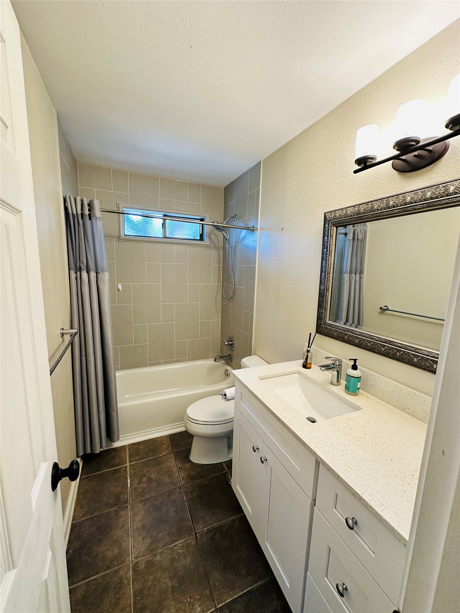 13015 Garfield Lane Austin, TX 78727 - Photo 9 of 16 Full bathroom with vanity, shower / bath combo, and dark tile patterned flooring
