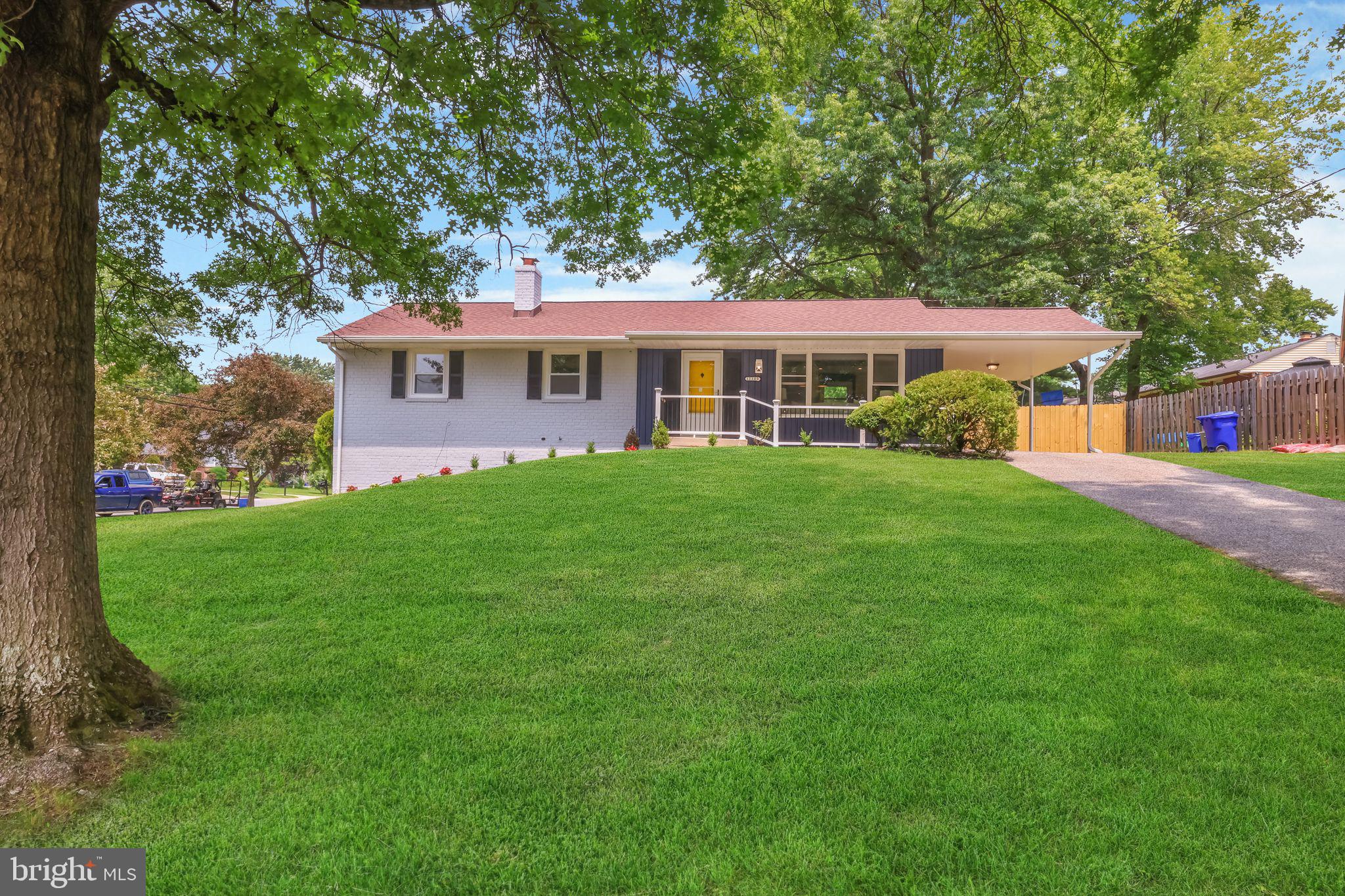 a view of a house next to a big yard and large trees