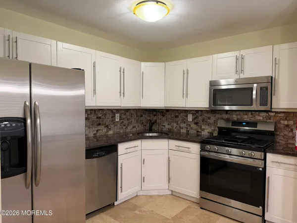 a kitchen with granite countertop white cabinets stainless steel appliances and a sink
