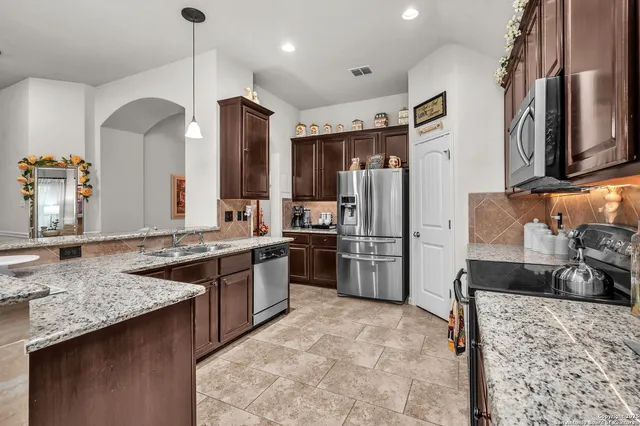 a kitchen with stainless steel appliances granite countertop a sink stove and refrigerator