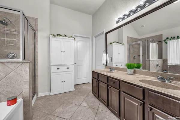 a spacious bathroom with a double vanity sink a mirror and a shower