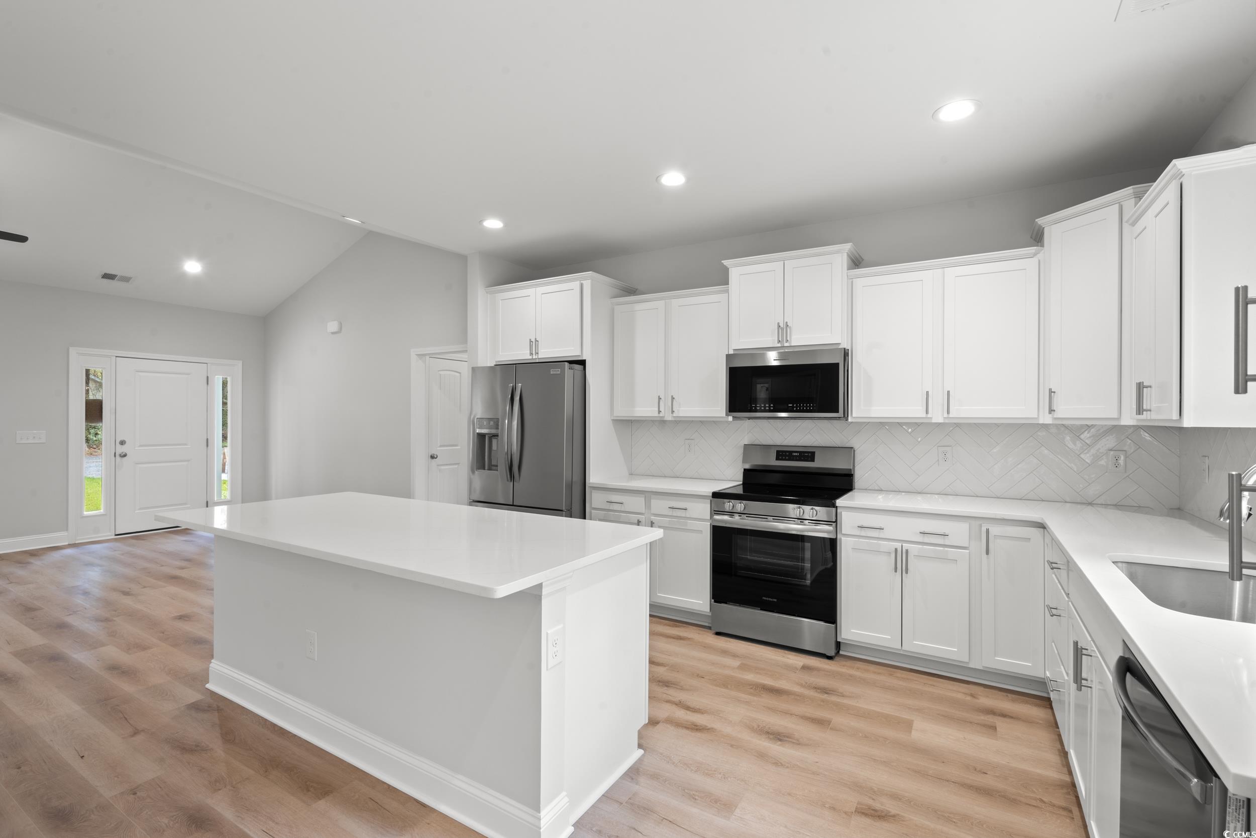 220 Ford Road Pawleys Island, SC 29585 - Photo 2 of 18 Kitchen featuring appliances with stainless steel finishes, vaulted ceiling, backsplash, recessed lighting, and white cabinets