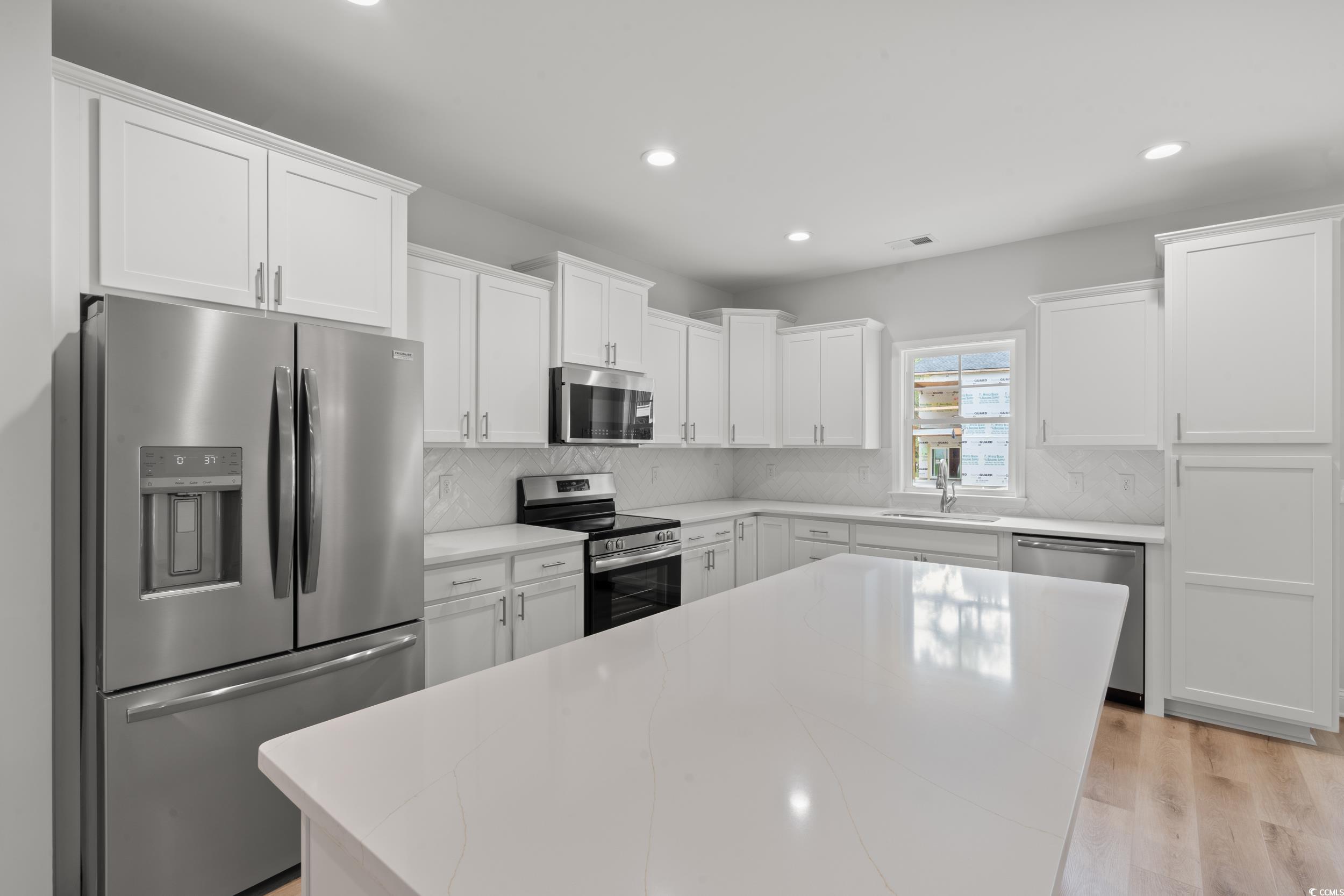 220 Ford Road Pawleys Island, SC 29585 - Photo 3 of 18 Kitchen with stainless steel appliances, white cabinets, backsplash, recessed lighting, and light wood-style flooring