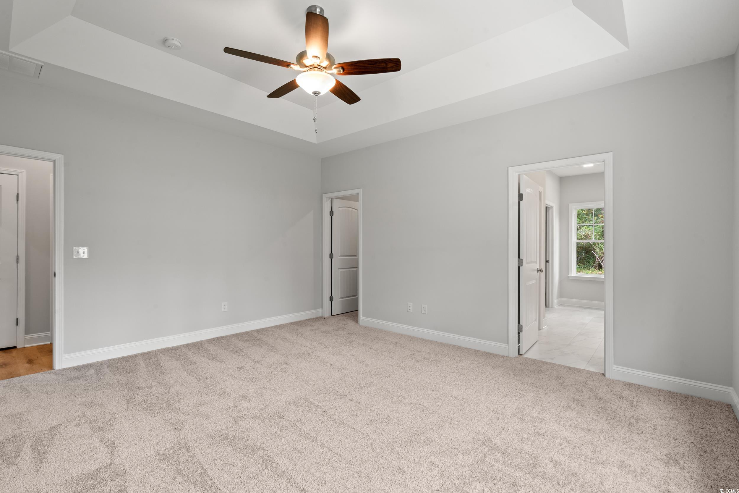 220 Ford Road Pawleys Island, SC 29585 - Photo 4 of 18 Unfurnished bedroom with a tray ceiling, light carpet, ceiling fan, and connected bathroom