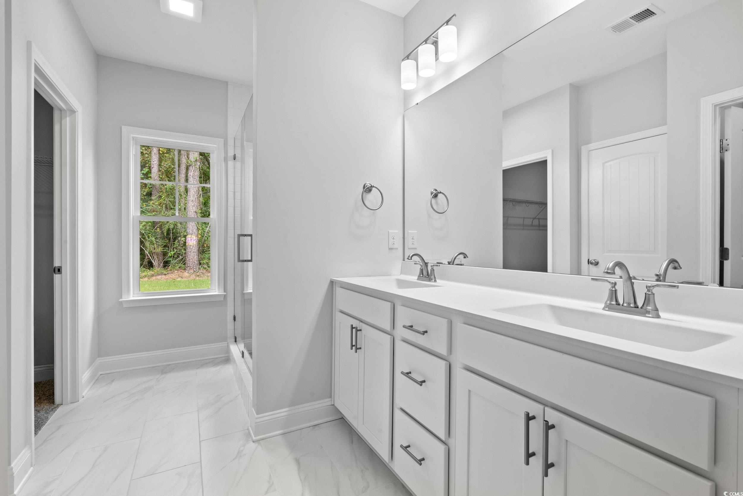 220 Ford Road Pawleys Island, SC 29585 - Photo 7 of 18 Bathroom with double vanity, light marble finish floors, and a stall shower