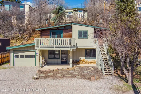 a view of a house with a yard and large tree