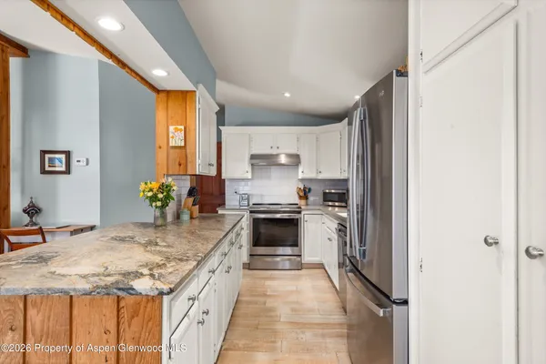 a large kitchen with granite countertop a sink and stainless steel appliances