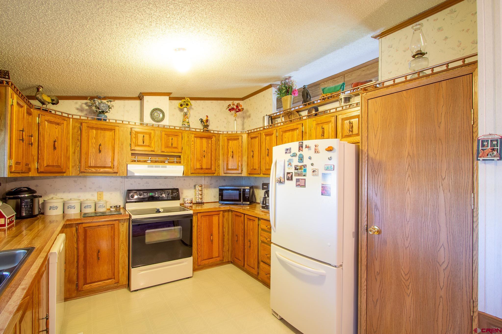 13648 B Road Delta, CO 81416 - Photo 17 of 35 a kitchen with stainless steel appliances granite countertop a refrigerator a stove and a sink with wooden floor